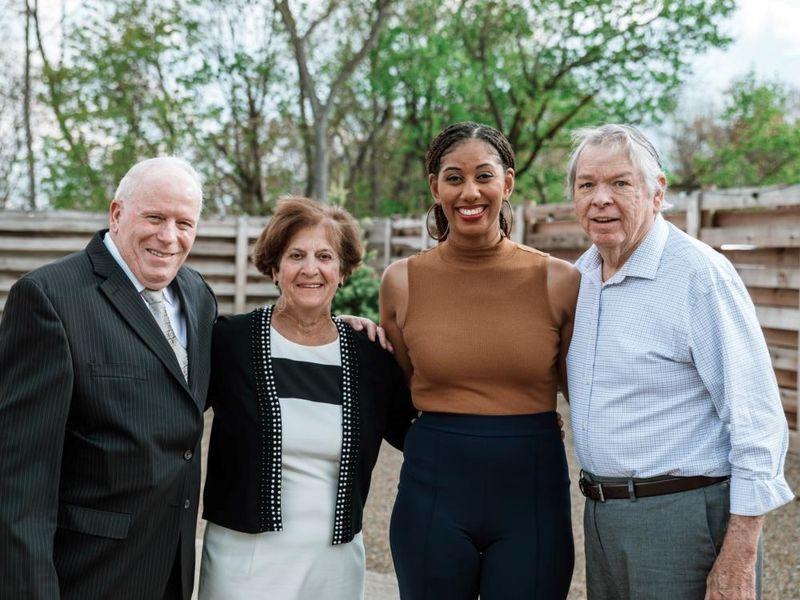 Four individuals stand smiling and posing for photo