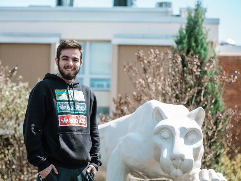 Student stands next to lion statue